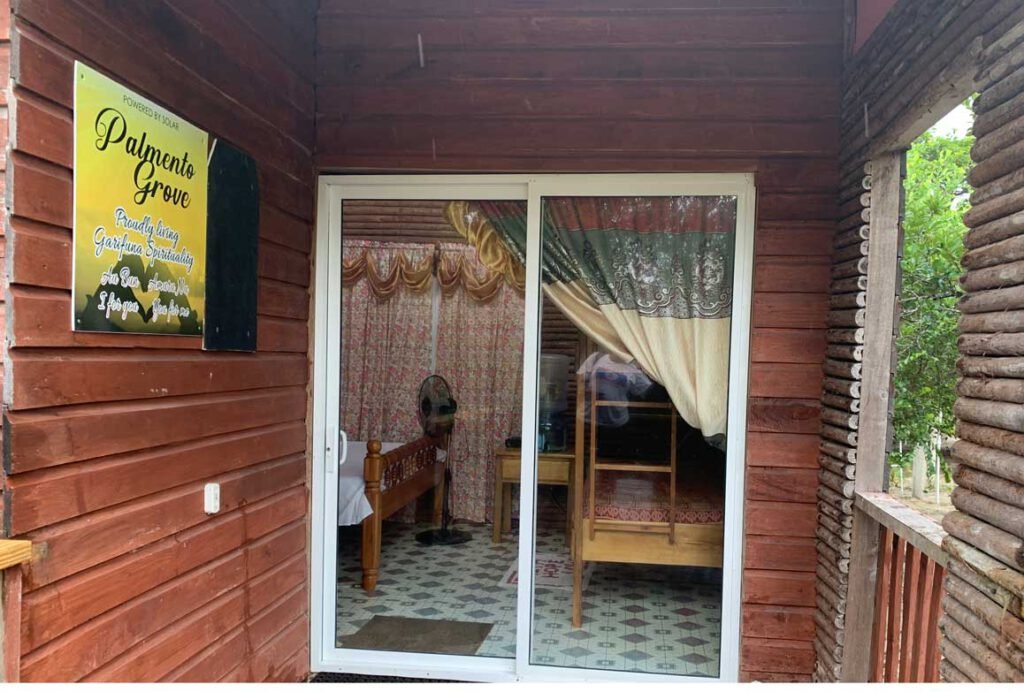 Porch and sliding glass door of a wooden guest cabin at Palmento Grove, Kalipuna Island, Belize