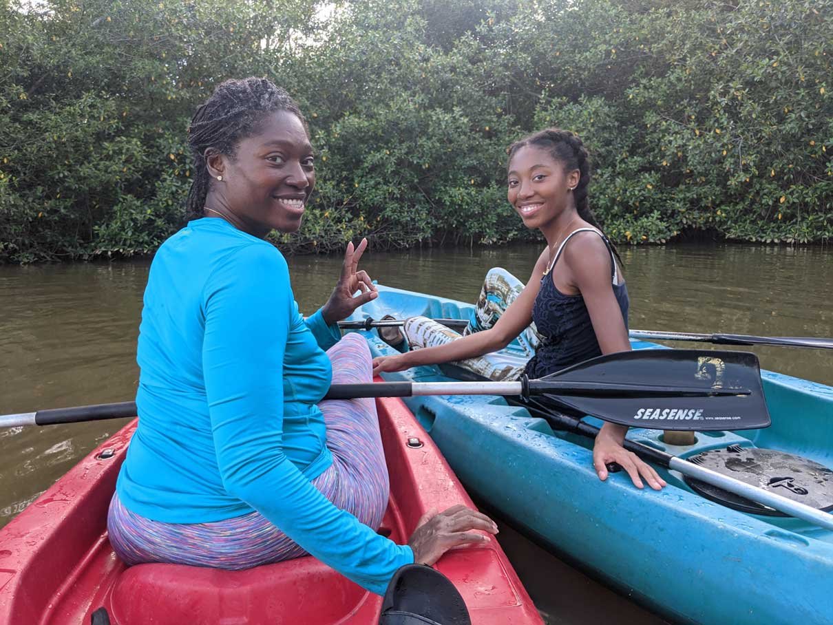 Two guests smiling in a kayak on the lagoon, Hopkins, Belize