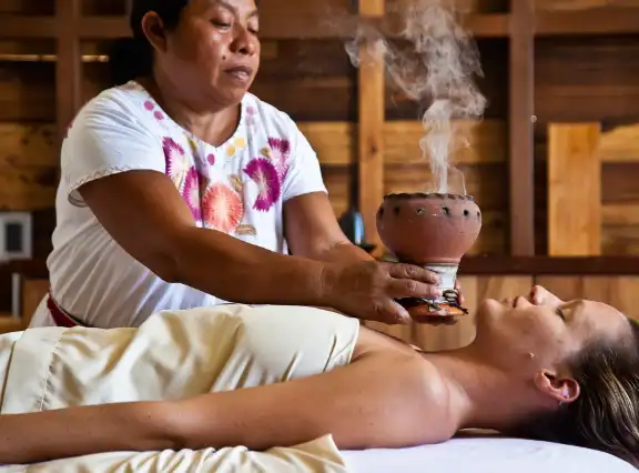 Maya healer holding a smoking copal burner over a guest during a healing session, Belize
