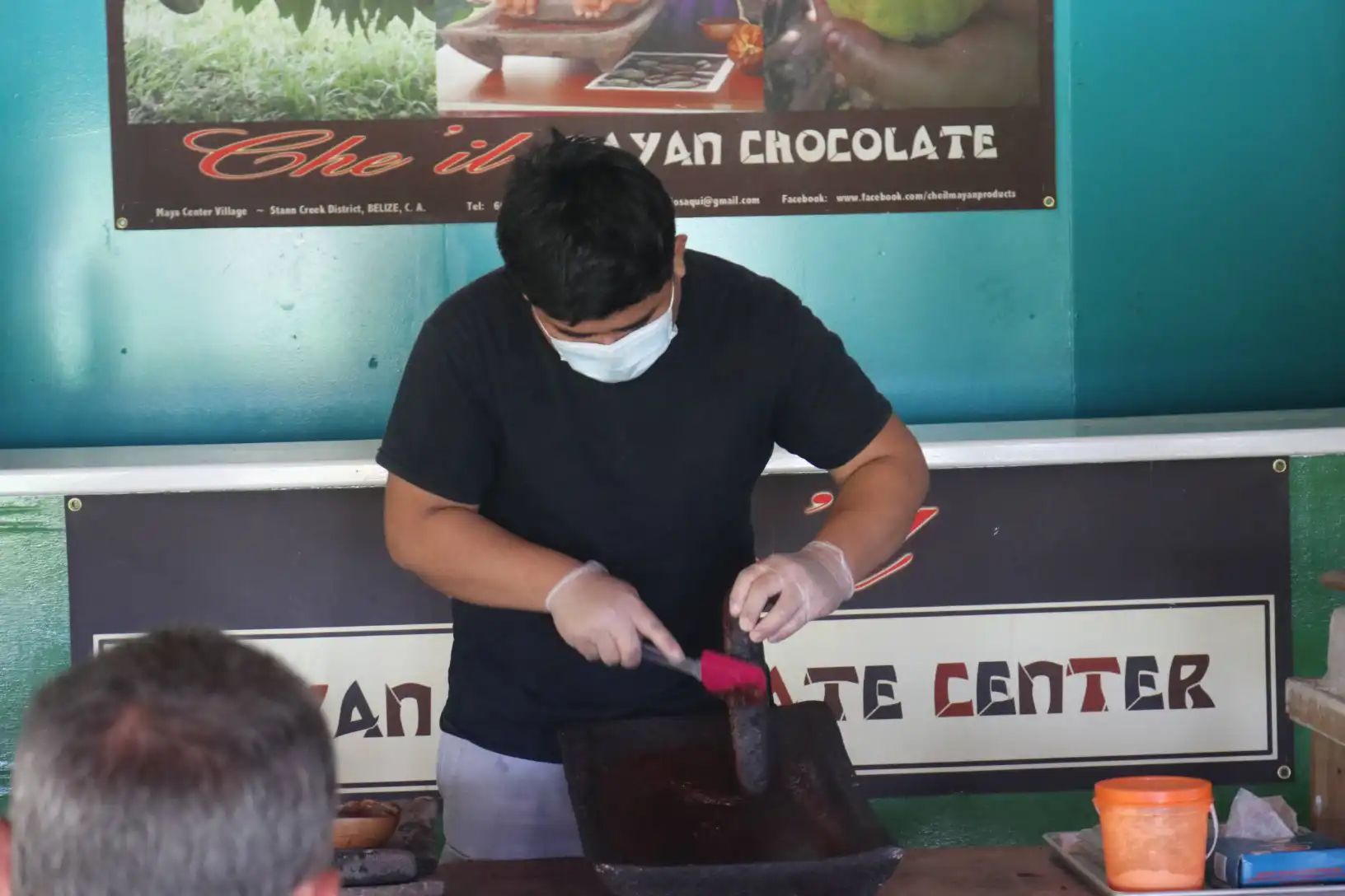 Chocolate maker in gloves and mask at work in the Maya chocolate centre, Belize