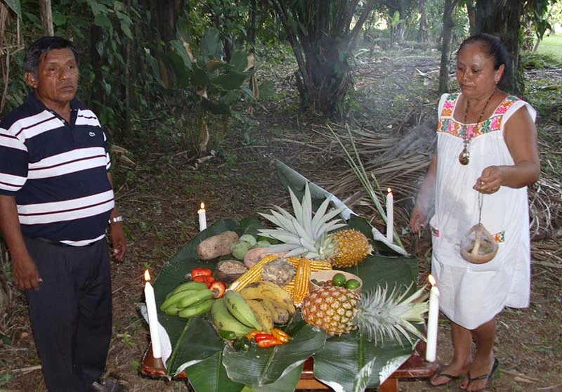 Maya healers standing behind an altar of fruit, candles and flowers in southern Belize