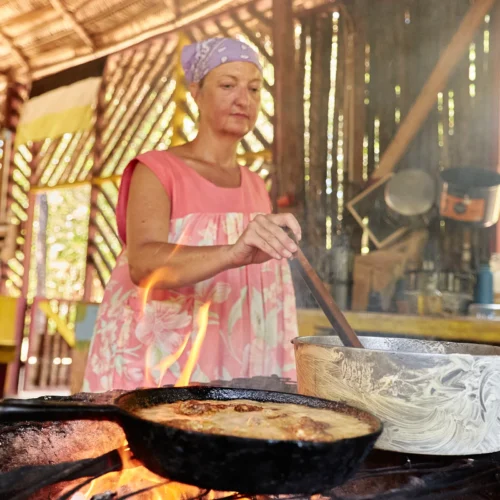 A cook frying over the open hearth in the Palmento Grove kitchen, Hopkins, Belize