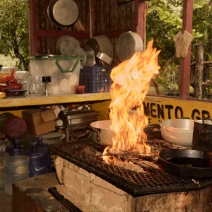 Tall flames under a cast-iron pan on the open-fire hearth at Palmento Grove, Hopkins, Belize