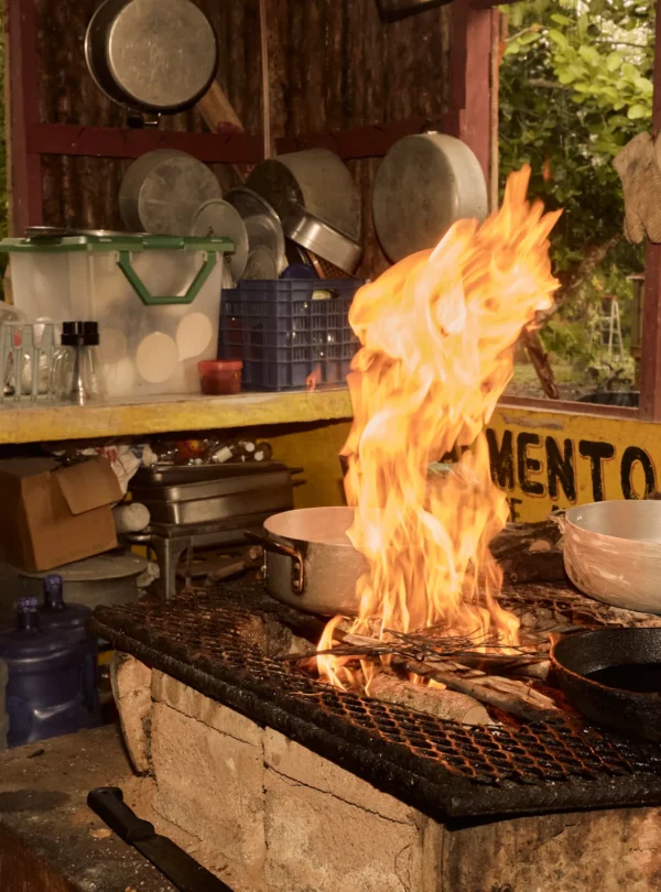 Tall flames under a cast-iron pan on the open-fire hearth at Palmento Grove, Hopkins, Belize
