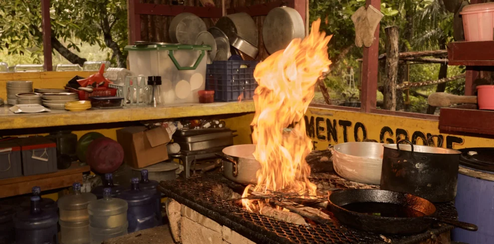 Tall flames under a cast-iron pan on the open-fire hearth at Palmento Grove, Hopkins, Belize
