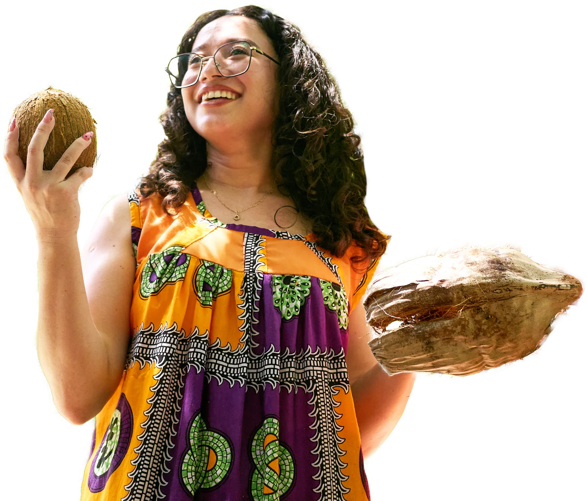 A guest in a Garifuna flag-colour dress holding a coconut at Palmento Grove, Hopkins, Belize