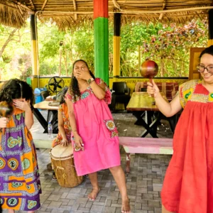 Guests dancing with maracas while drummers play in the Buiti Achuluruni pavilion at Palmento Grove, Hopkins, Belize