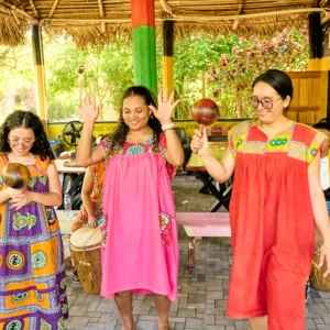Guests dancing with raised hands and maracas in the drum pavilion at Palmento Grove, Hopkins, Belize