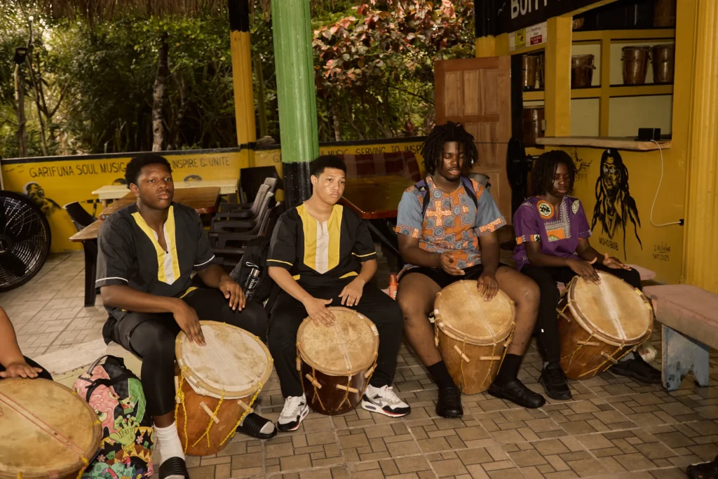 A Garifuna drumming and dancing session with guests playing the drums at Palmento Grove