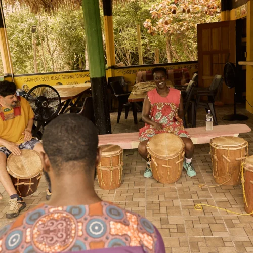 A drumming instructor teaching guests with Garifuna drums in the foreground at Palmento Grove, Hopkins, Belize