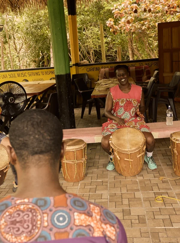A drumming instructor teaching guests with Garifuna drums in the foreground at Palmento Grove, Hopkins, Belize
