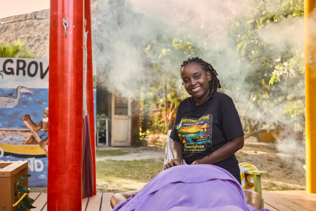 Tyana "Tee" Nunez, the massage therapist, smiling beside a guest on the massage deck at Palmento Grove, Hopkins, Belize