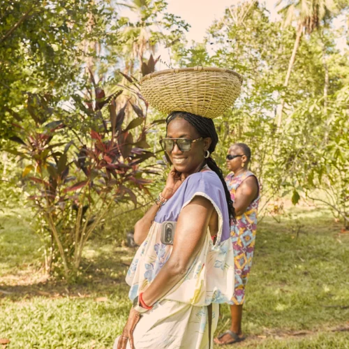 Carrying a woven basket on the head through the garden at Palmento Grove, Hopkins, Belize