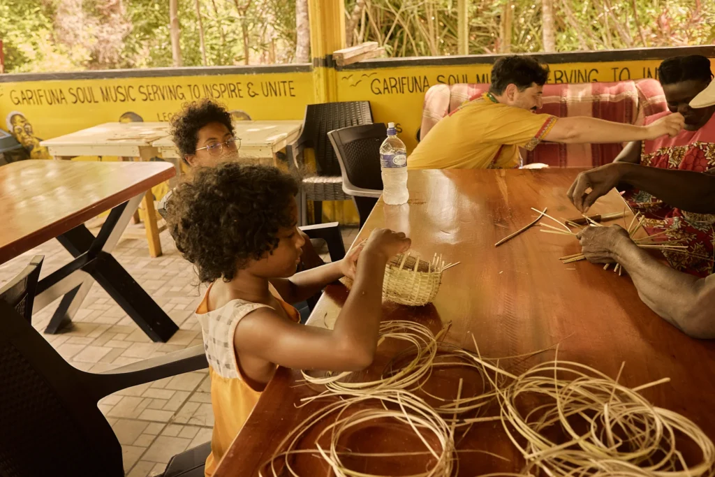 Hands weaving a basket from reeds during a craft session at Palmento Grove, Hopkins, Belize
