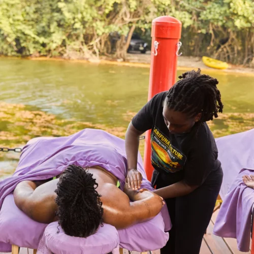 A Palmento Grove therapist working on a guest's shoulders on the massage deck over Fresh Water Creek Lagoon, Hopkins, Belize