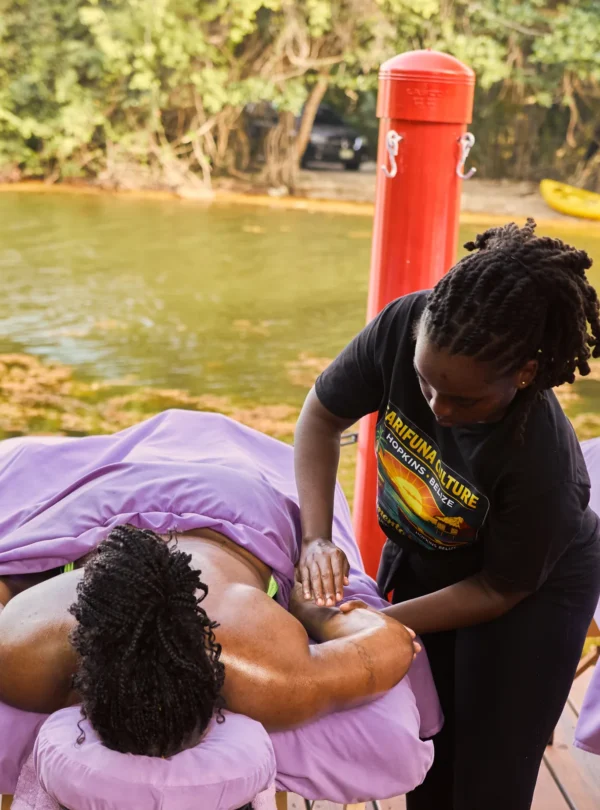 A Palmento Grove therapist working on a guest's shoulders on the massage deck over Fresh Water Creek Lagoon, Hopkins, Belize