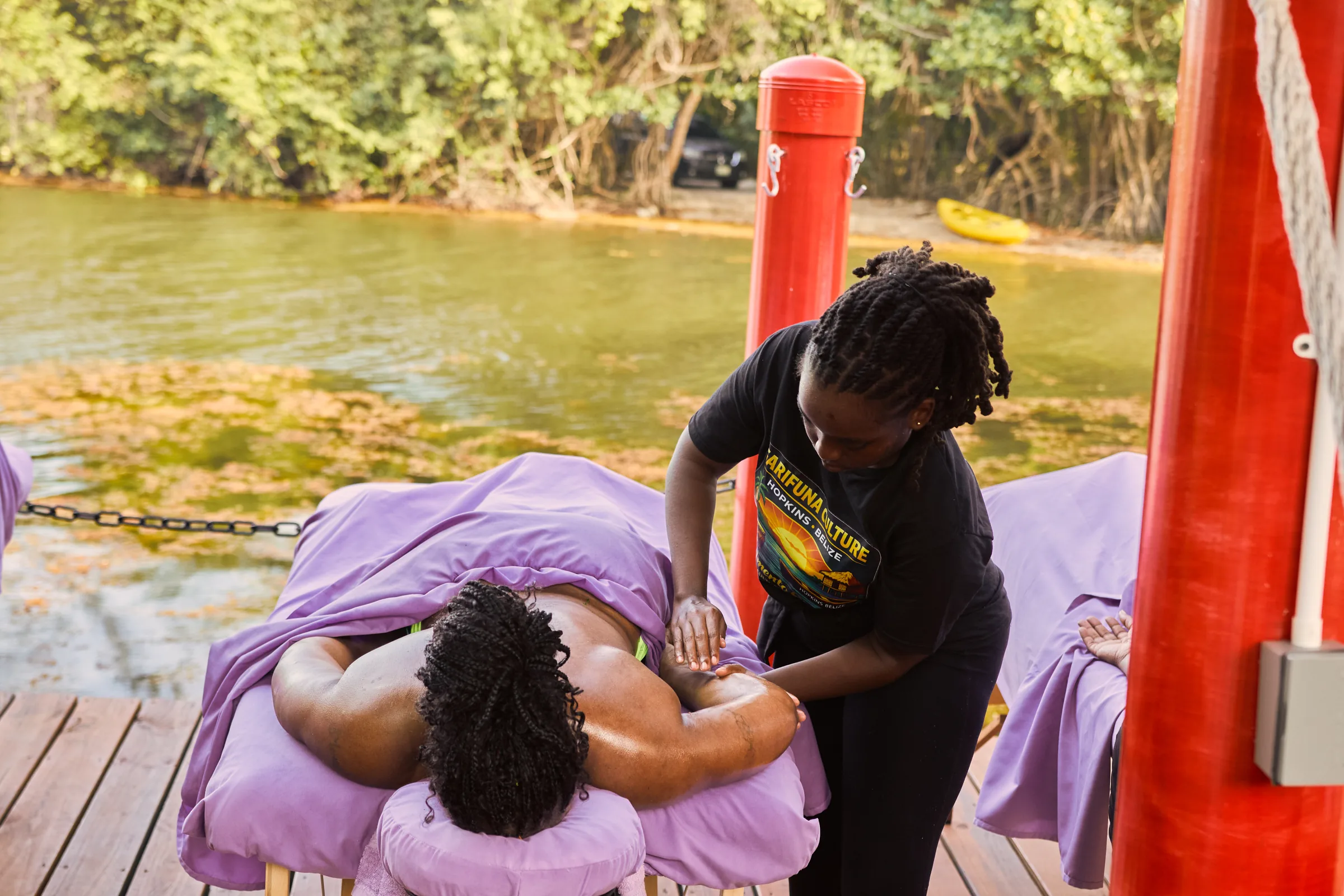 A Palmento Grove therapist working on a guest's shoulders on the massage deck over Fresh Water Creek Lagoon